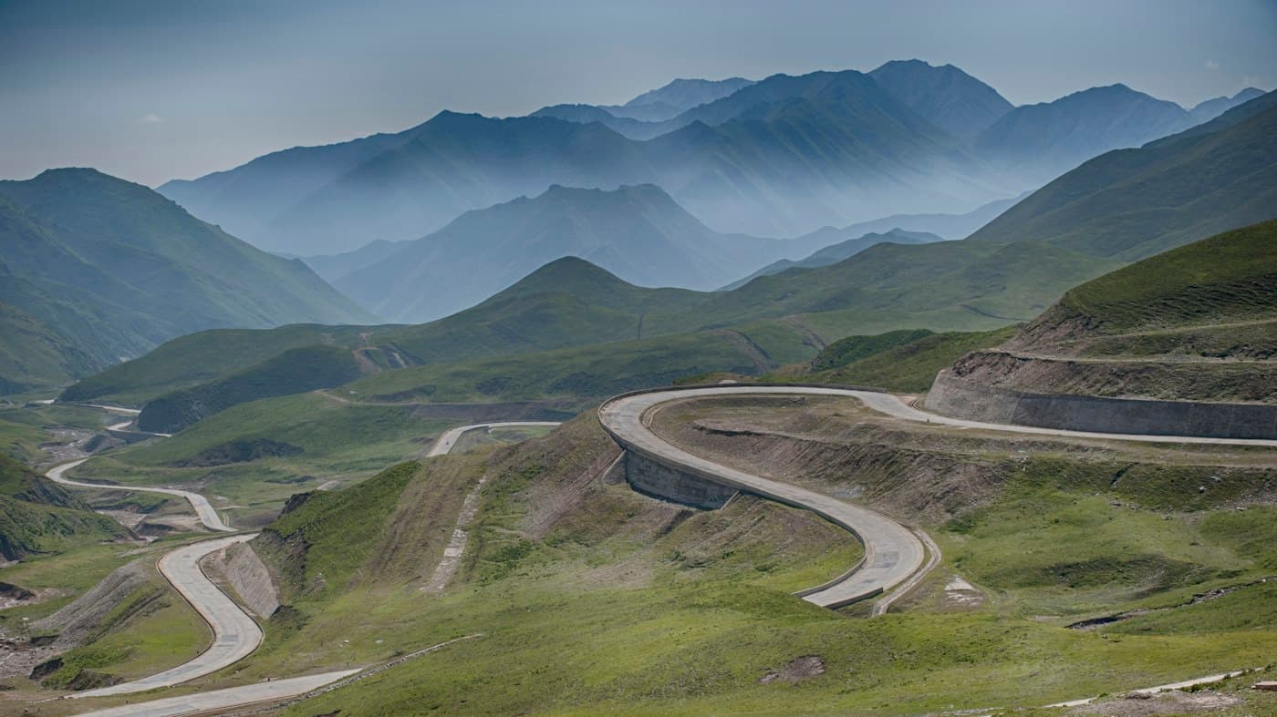 A road winding in switchbacks through green mountain terrain